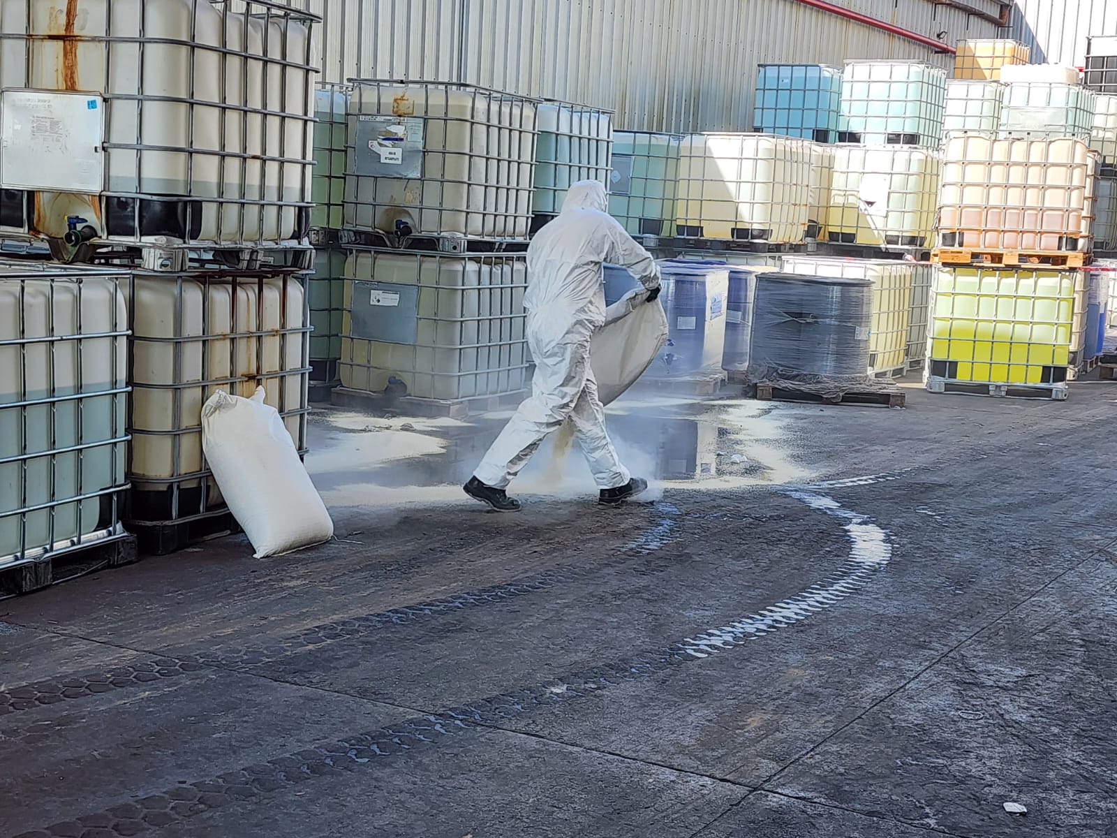 Operario con traje de protección química conteniendo derrame en depósito